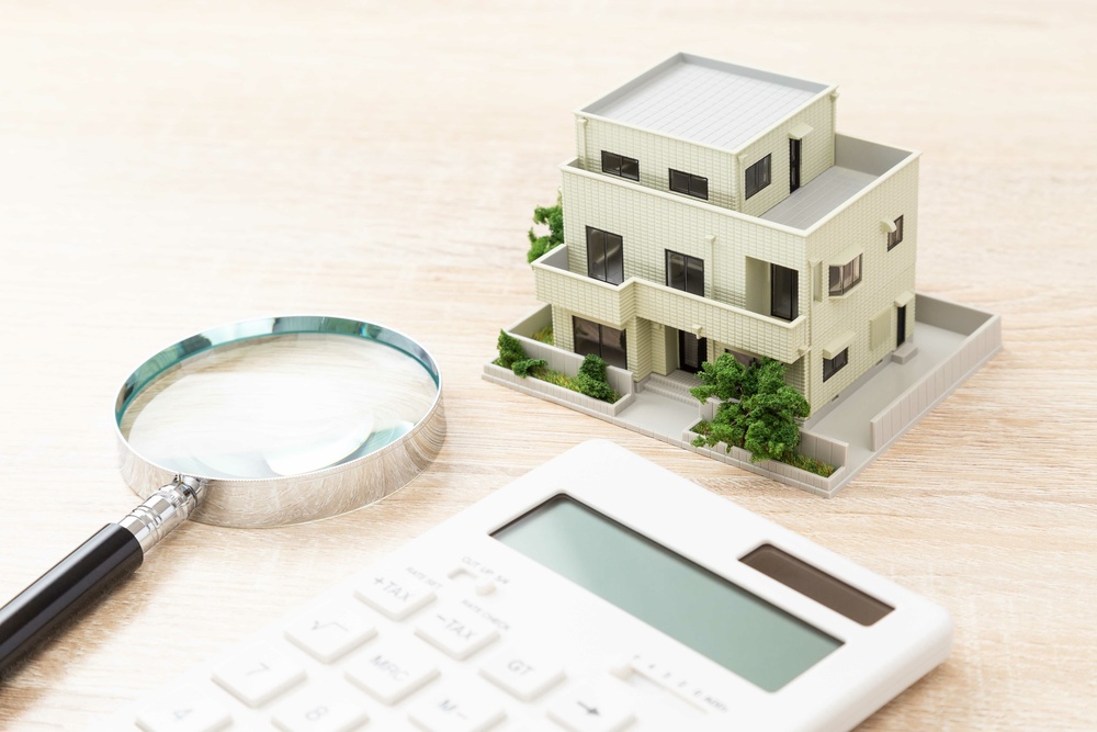 住宅模型と電卓と虫眼鏡